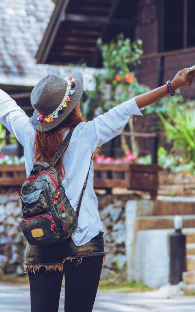 Freedom traveler woman standing with raised a book in hand arms and enjoying a beautiful nature. space for text.