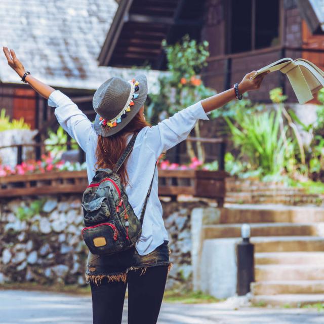 Freedom traveler woman standing with raised a book in hand arms and enjoying a beautiful nature. space for text.