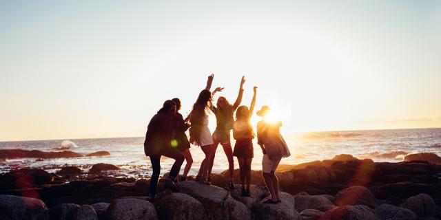 Hipster fun loving friends dancing at beach on sunset