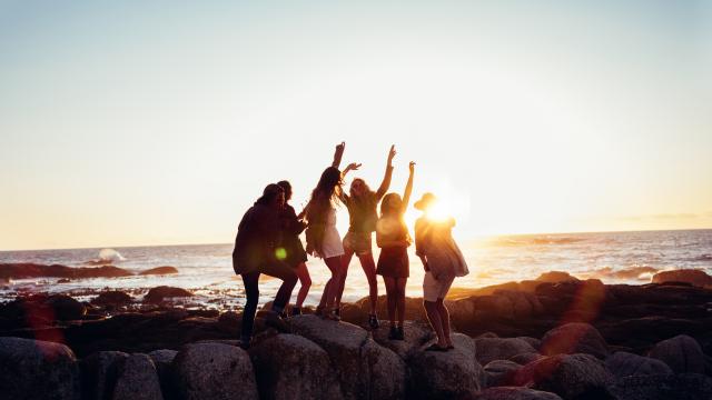 Hipster fun loving friends dancing at beach on sunset