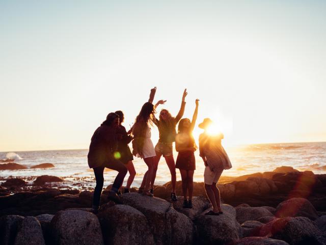 Hipster fun loving friends dancing at beach on sunset