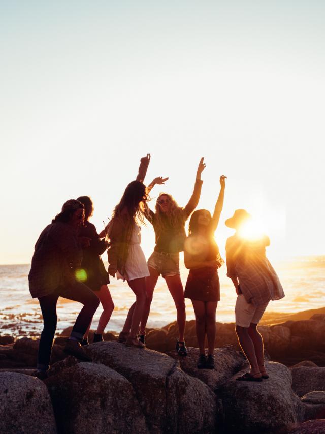 Hipster fun loving friends dancing at beach on sunset