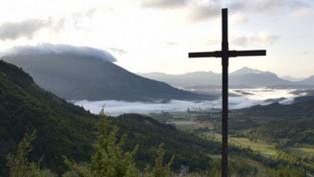 Petit chemin menant à une croix dans la montagne à l'aube, brume dans la vallée, montagnes dans le lointain, La Beaume, Hautes Alpes, France, Août 2018