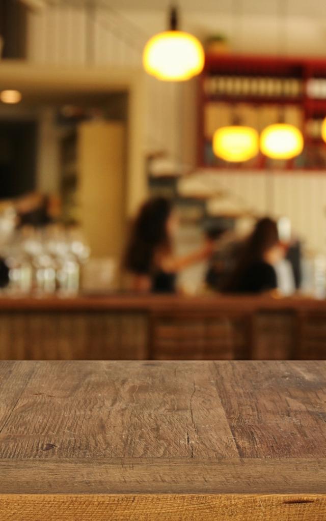 Image of wooden table in front of abstract blurred restaurant lights background