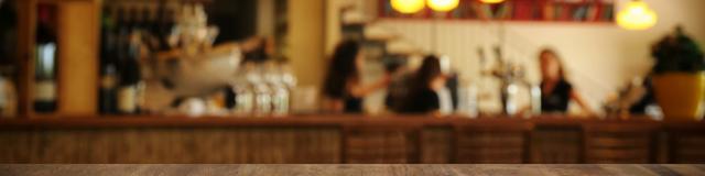 Image of wooden table in front of abstract blurred restaurant lights background