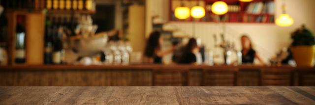 Image of wooden table in front of abstract blurred restaurant lights background