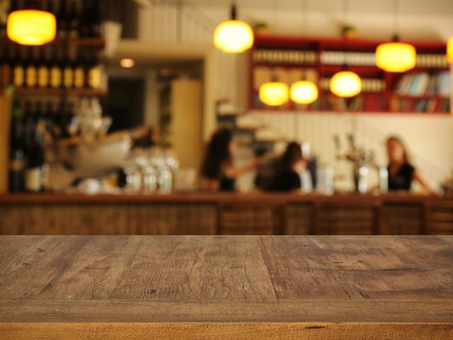 Image of wooden table in front of abstract blurred restaurant lights background