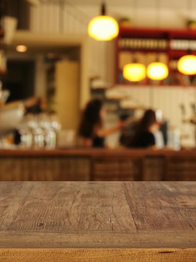 Image of wooden table in front of abstract blurred restaurant lights background