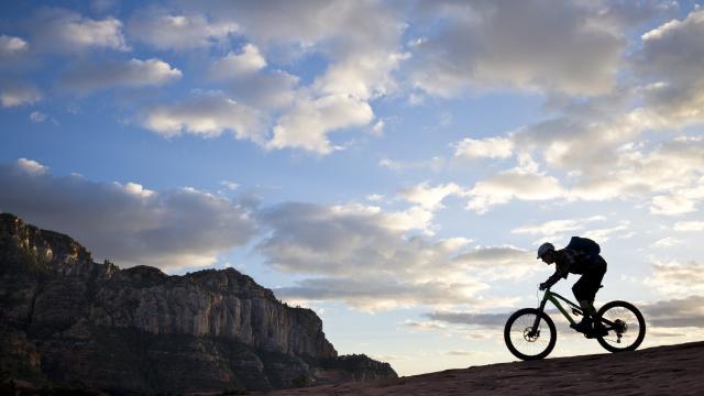 A man rides his enduro-style mountain bike at sunset in Sedona, Arizona, USA.