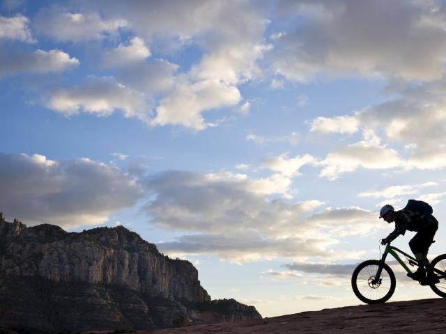 A man rides his enduro-style mountain bike at sunset in Sedona, Arizona, USA.