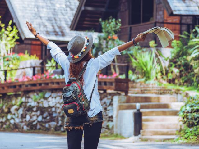 Freedom traveler woman standing with raised a book in hand arms and enjoying a beautiful nature. space for text.