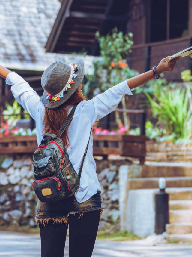 Freedom traveler woman standing with raised a book in hand arms and enjoying a beautiful nature. space for text.