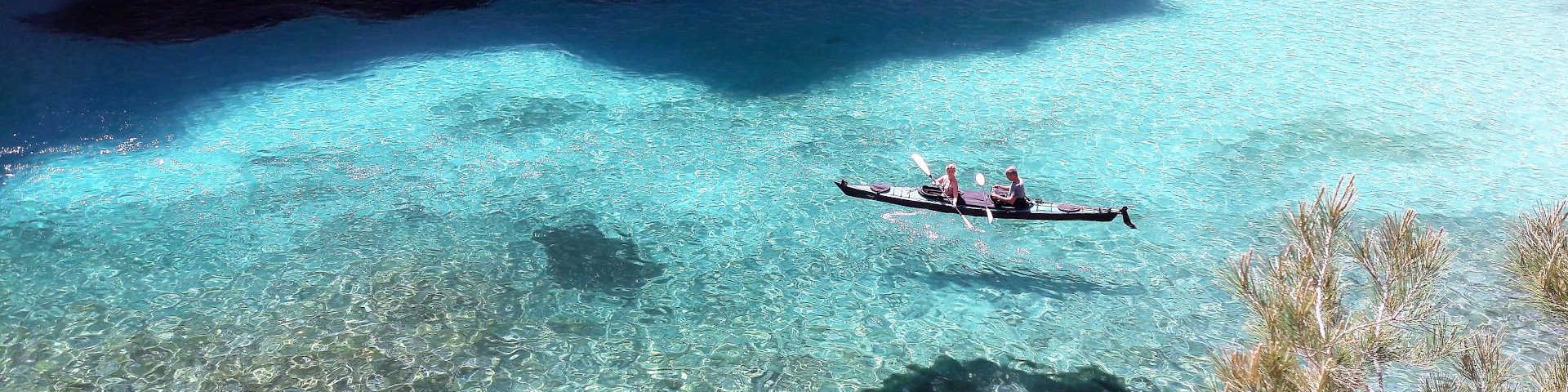 A kayak floating on the transparent water of the En-Vau cove