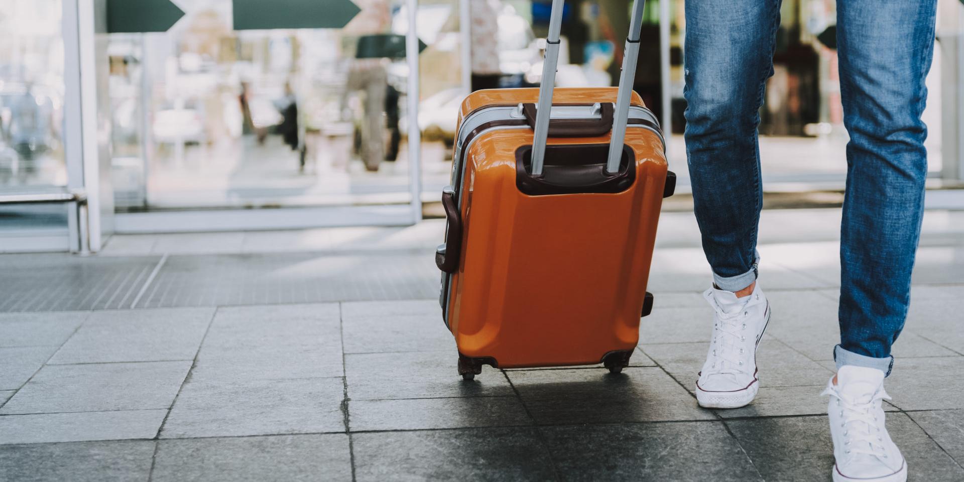Close-up of man walking with suitcase. He is going in departure lounge. Copy space in left side