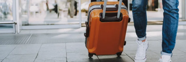 Close-up of man walking with suitcase. He is going in departure lounge. Copy space in left side