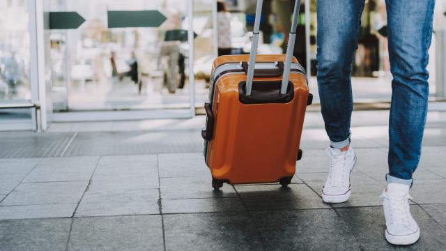 Close-up of man walking with suitcase. He is going in departure lounge. Copy space in left side