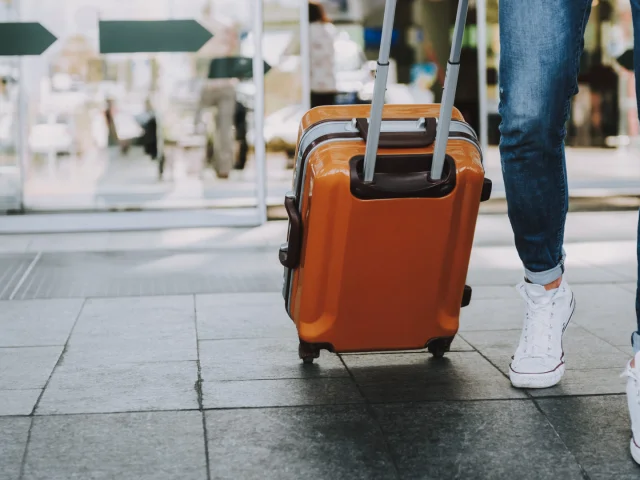 Close-up of man walking with suitcase. He is going in departure lounge. Copy space in left side