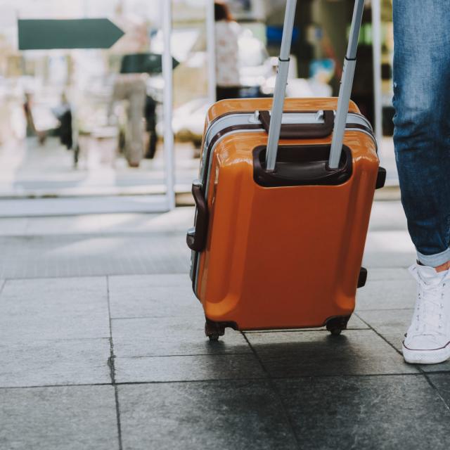 Close-up of man walking with suitcase. He is going in departure lounge. Copy space in left side