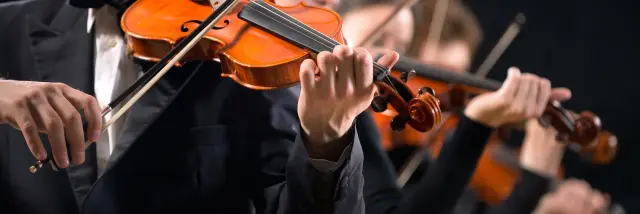 Violinists performing on stage on dark background.