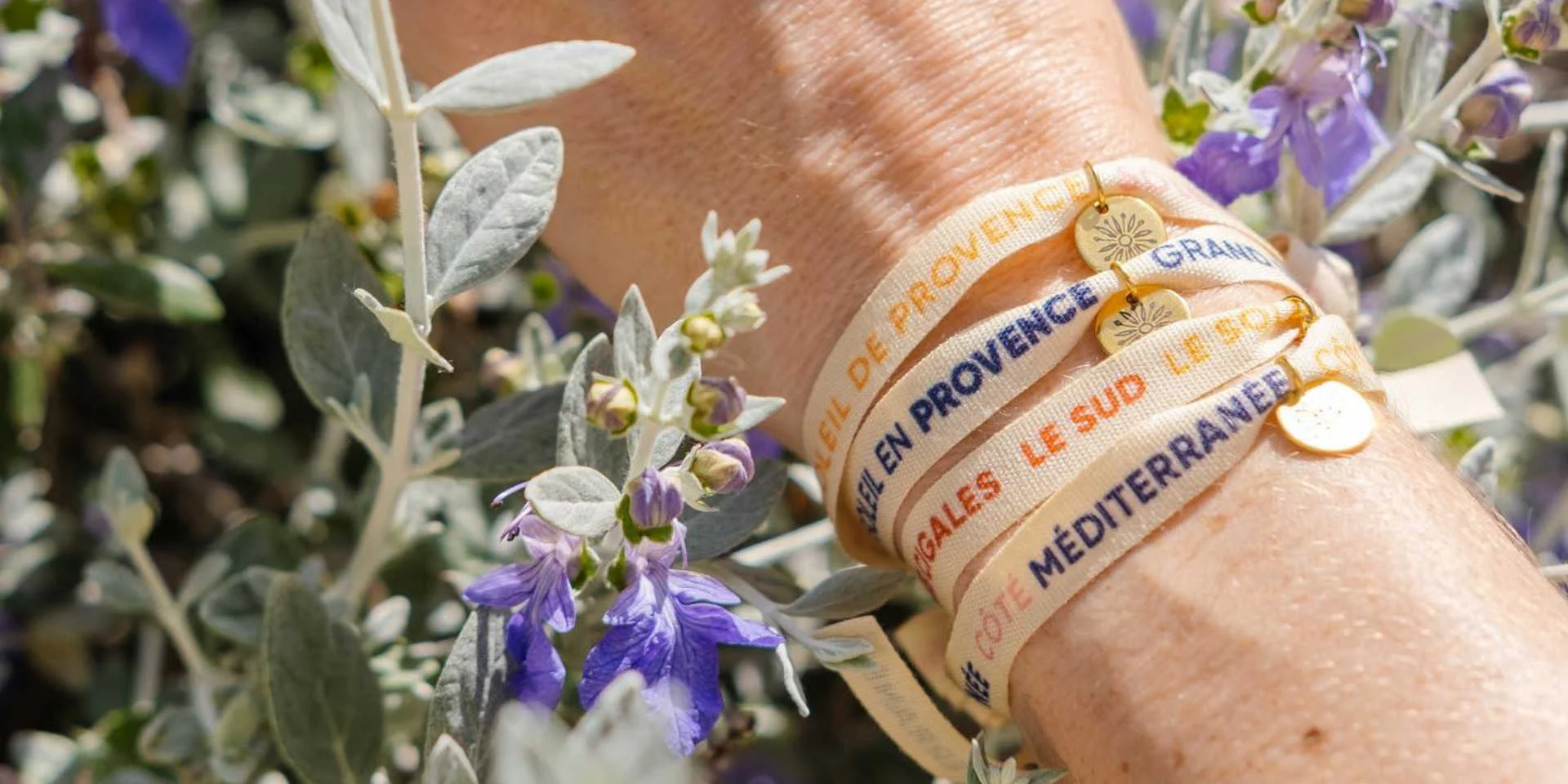 Plusieurs bracelets rubans sur un poignet dans les fleurs