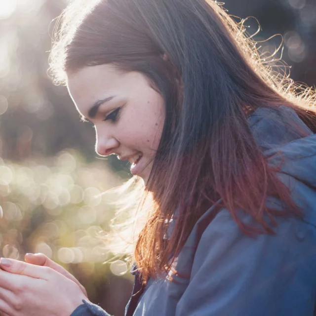 Femme en imperméable qui consulte son smartphone