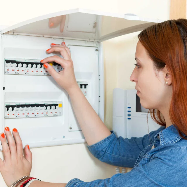 Femme qui éteint l'électricité sur un tableau électrique