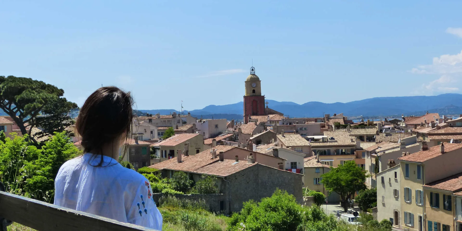 Junge Frau sitzt auf einer Bank auf den Höhen von Saint-Tropez