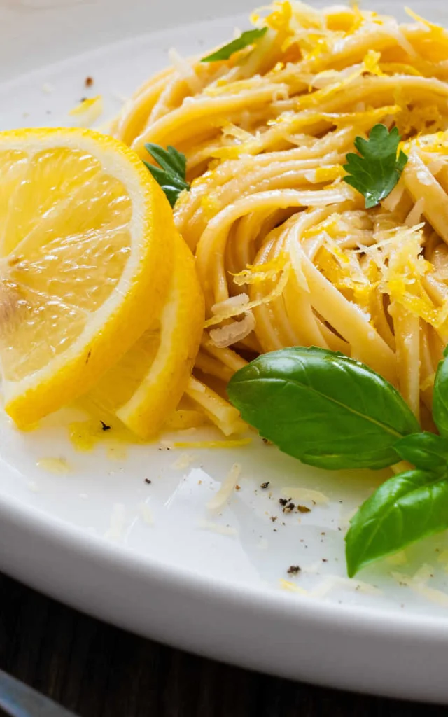 Gros plan sur une assiette de tagliatelles au citron avec un brin de basilic