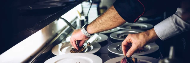 Mains de chefs cuisiniers qui dressent des plats dans un restaurant gastronomique