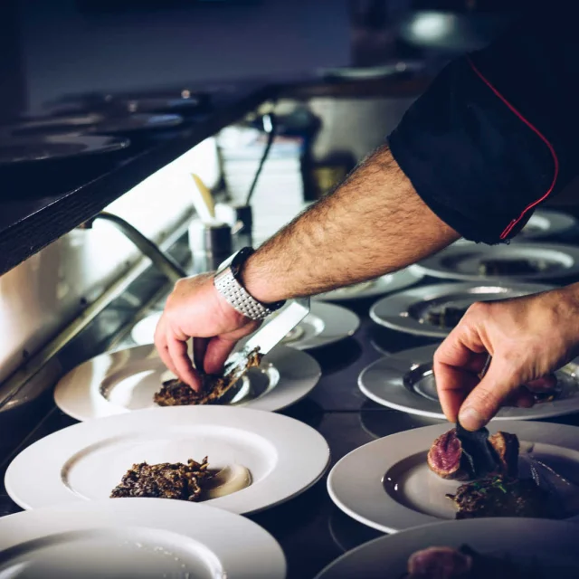 Mains de chefs cuisiniers qui dressent des plats dans un restaurant gastronomique