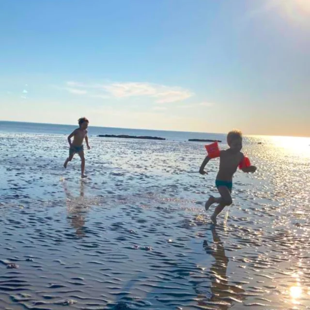 Des enfants qui courent sur la plage et dans la mer