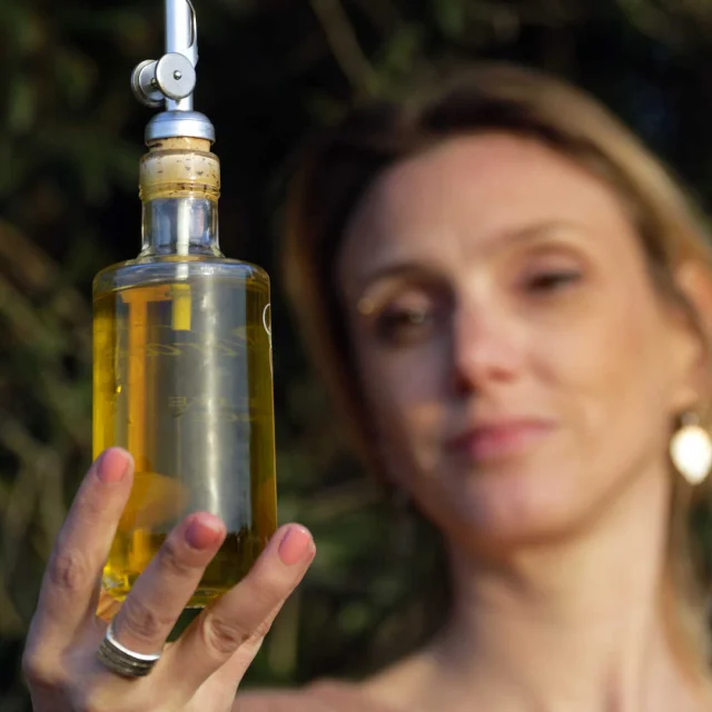 Une femme qui présente une bouteille d'huile d'olive du Château Virant à Salon-de-Provence