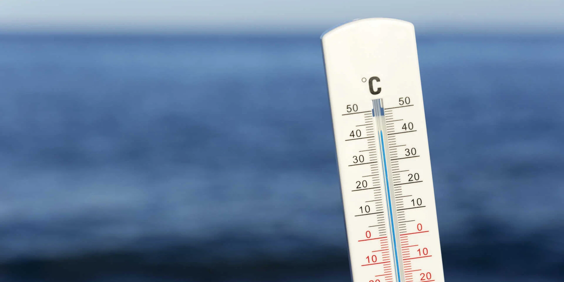 Un thermomètre blanc devant la mer et l'horizon