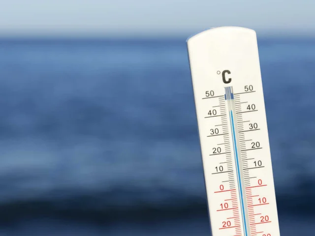 Un thermomètre blanc devant la mer et l'horizon