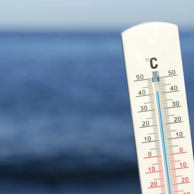 Un thermomètre blanc devant la mer et l'horizon