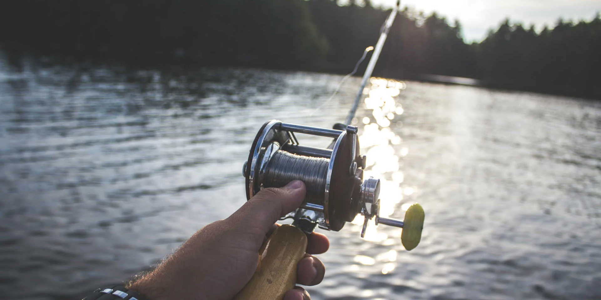 Fishing reel and mountain lake in the background