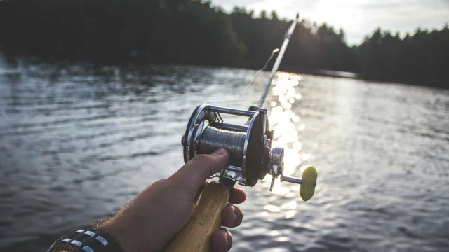 Gros plan sur un moulinet de pêche et lac de montagne en arrière-plan