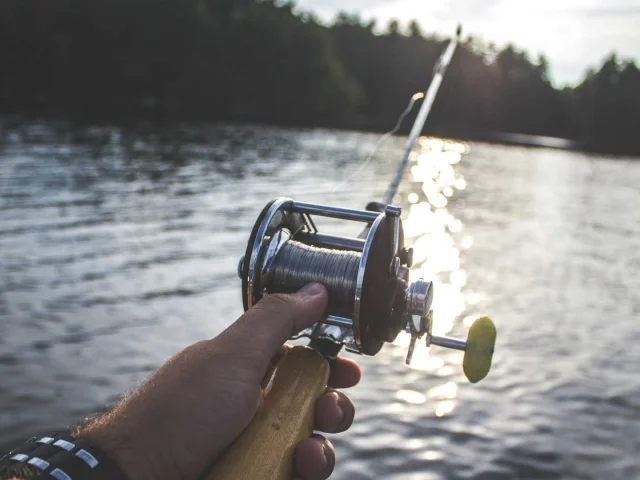 Fishing reel and mountain lake in the background