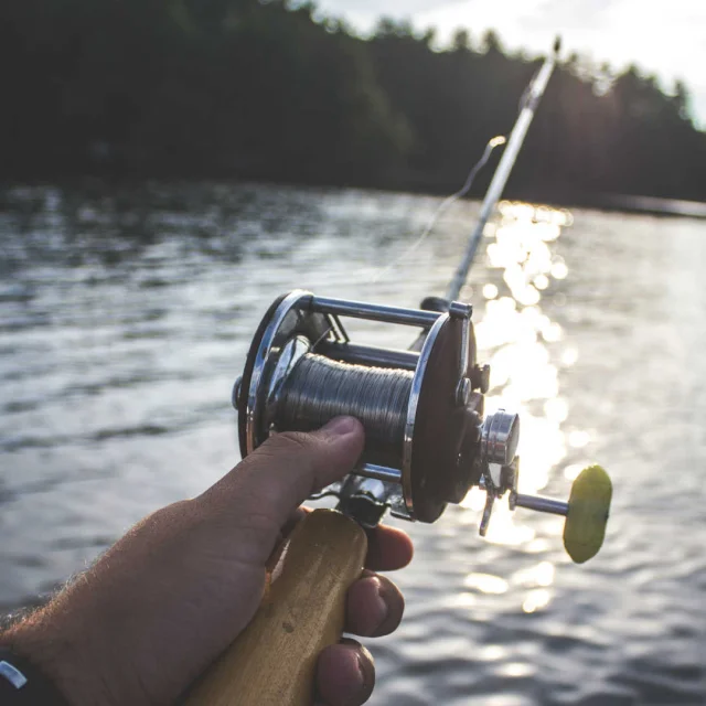 Gros plan sur un moulinet de pêche et lac de montagne en arrière-plan