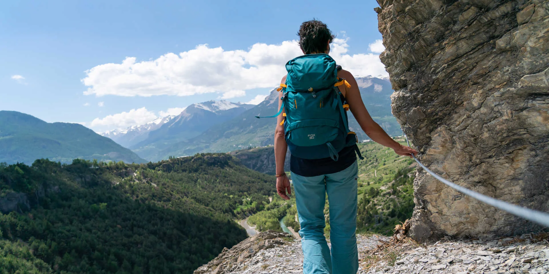 Randonneuse qui tient une main courante sur un sentier de randonnée du Queyras