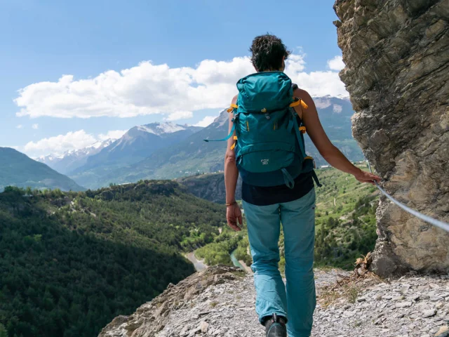 Randonneuse qui tient une main courante sur un sentier de randonnée du Queyras