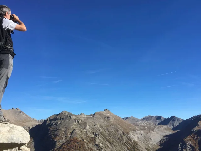 Un randonneur qui observe le panorama du Mercantour avec des jumelles