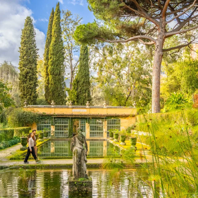 Deux visiteurs marchent au bord des bassins du jardin Serre de la Madone