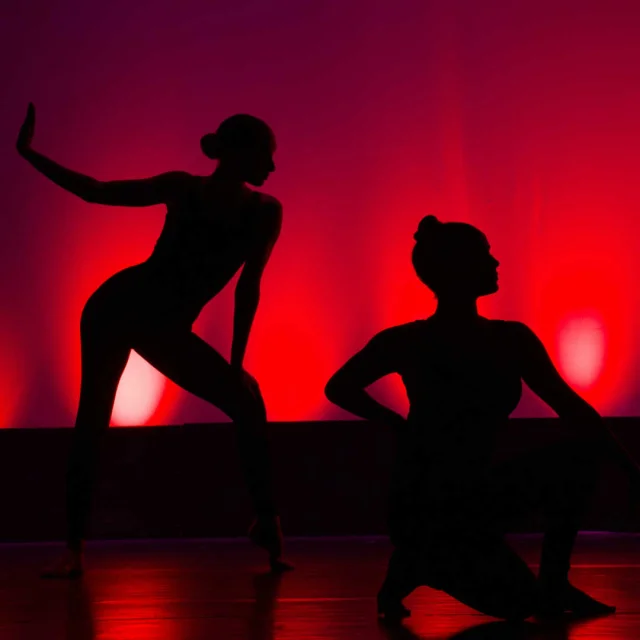 Trois silhouettes de danseuses dans la lumière rouge