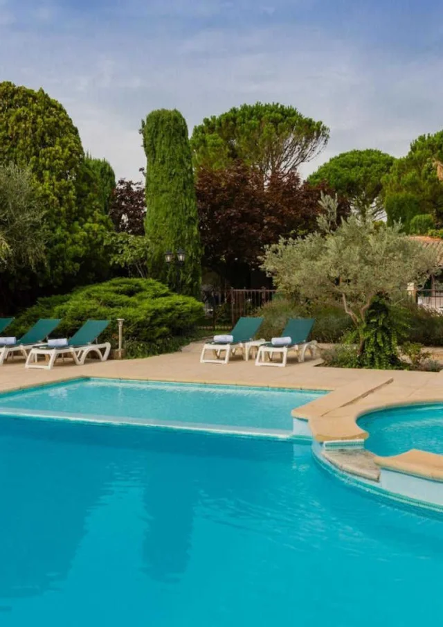 Une piscine et un espace détente entourés de verdure à l'Auberge de Cassagne