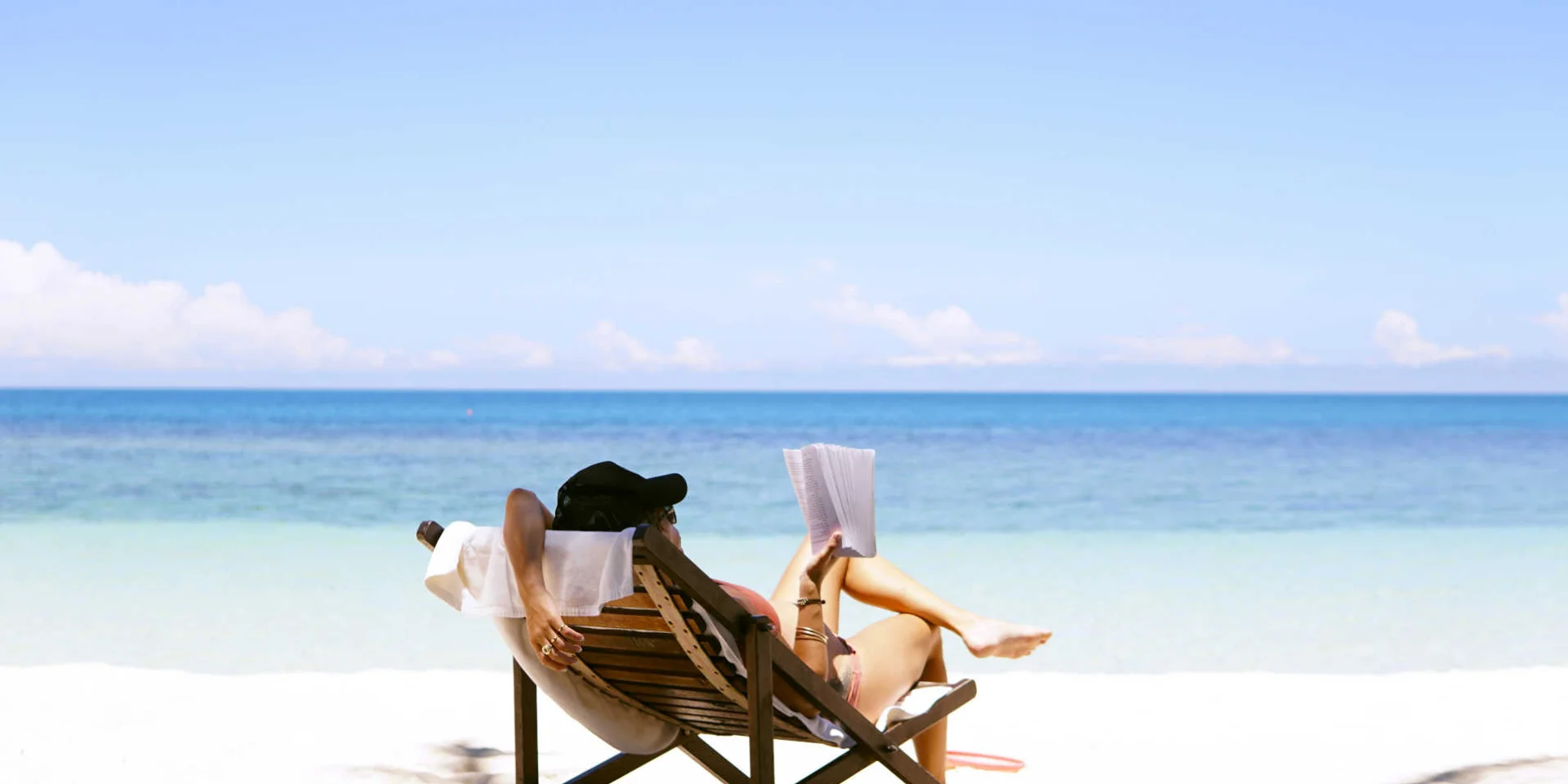 Femme sur un transat lisant à la plage
