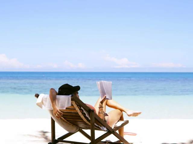 Femme sur un transat lisant à la plage