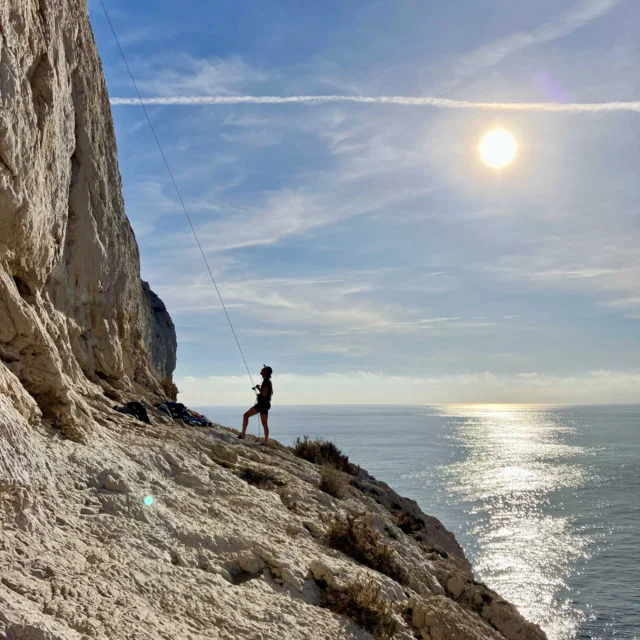 Un grimpeur qui assure son coéquipier dans les calanques face à la mer