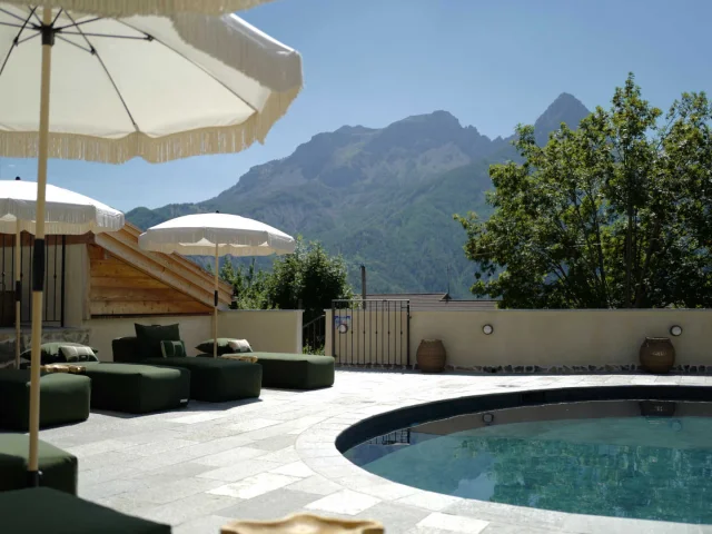 The swimming pool at the Hotel Le Prieuré de Pra Loup with the mountains in the background