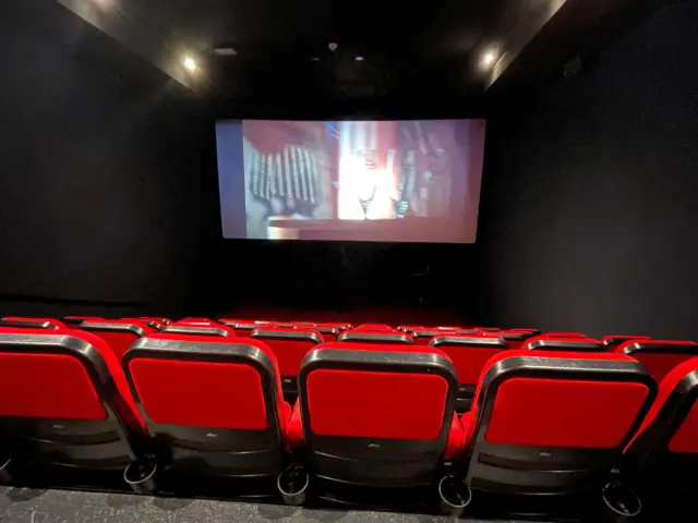 Les fauteuils rouges et l'écran d'une salle de cinéma